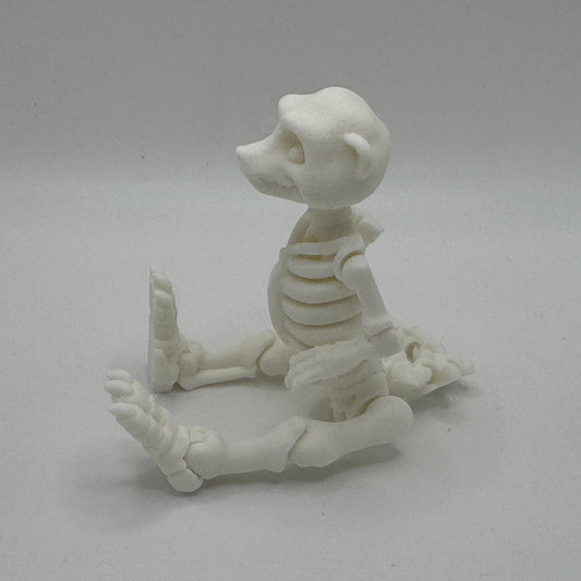White plastic sculpture of a cartoon meerkat skeleton design on a gray background