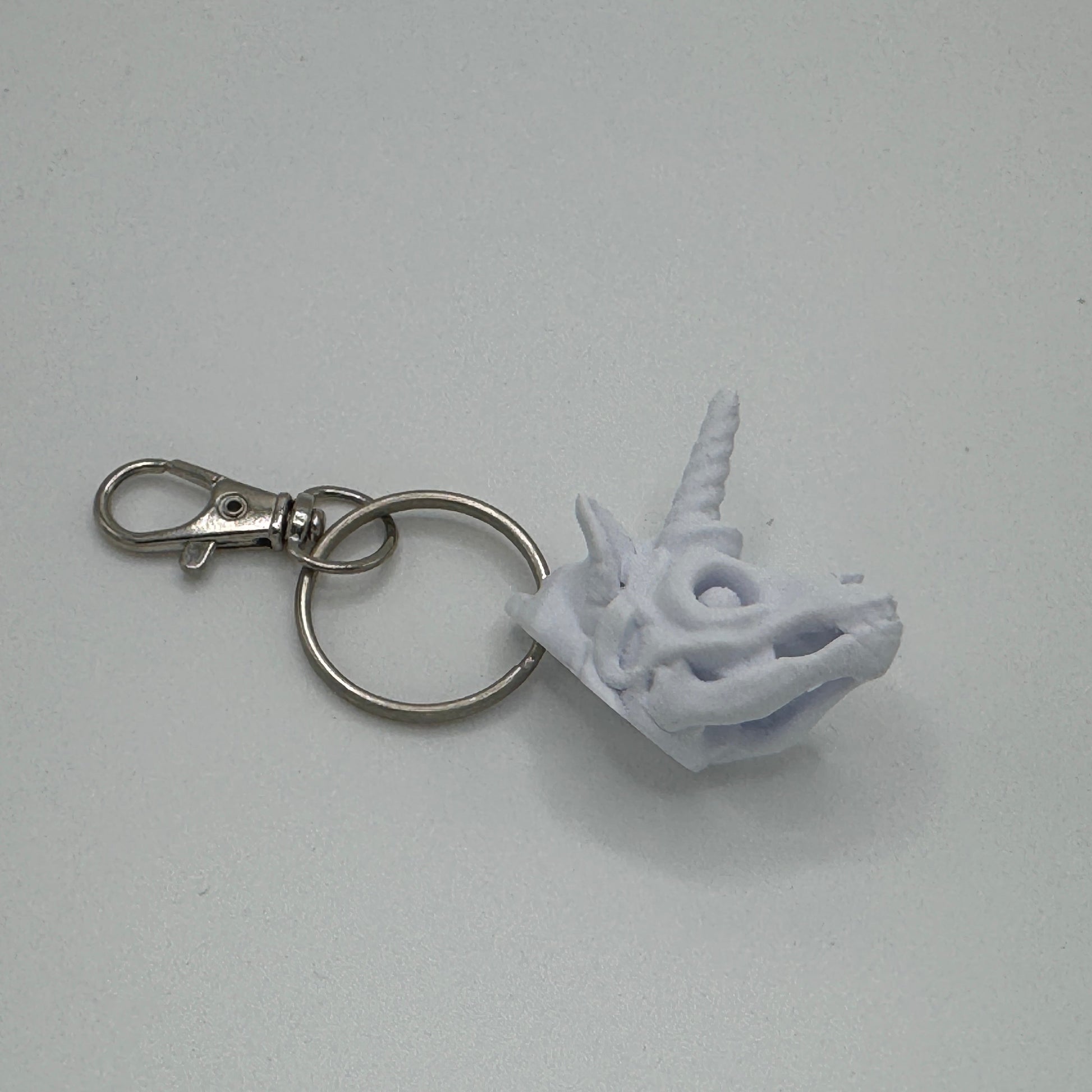 White unicorn head keychain on a gray background