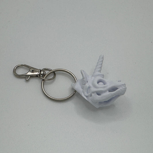 White unicorn head keychain on a gray background