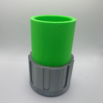 A 3D-printed container with a bright green cylindrical upper section and a gray lower base featuring vertical grooves. The object is hollow, with an open top, and is set against a plain light gray background.