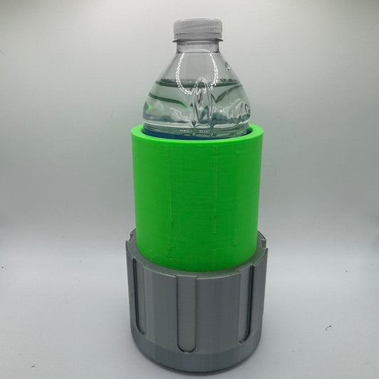 A small clear plastic water bottle sits inside a 3D-printed holder. The holder has two parts: a bright green cylindrical upper sleeve that wraps snugly around the bottle and a gray lower base with vertical groove details. The background is a plain light gray, and the image is well lit.