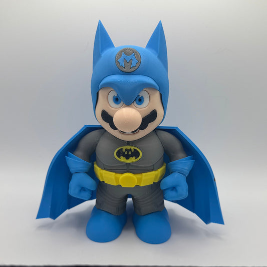 Toy figure of a Mario character wearing a blue cape and gray outfit with a Batman logo on a white background